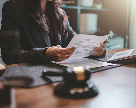 A professional woman reviewing documents at a desk with a gavel, suggesting legal work or judicial proceedings